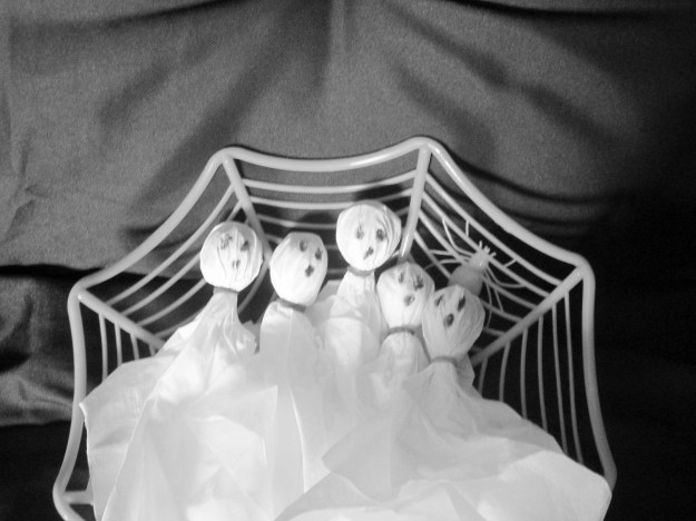 Ghosts made from lollipops covered with white napkins, fastened with a rubber band.